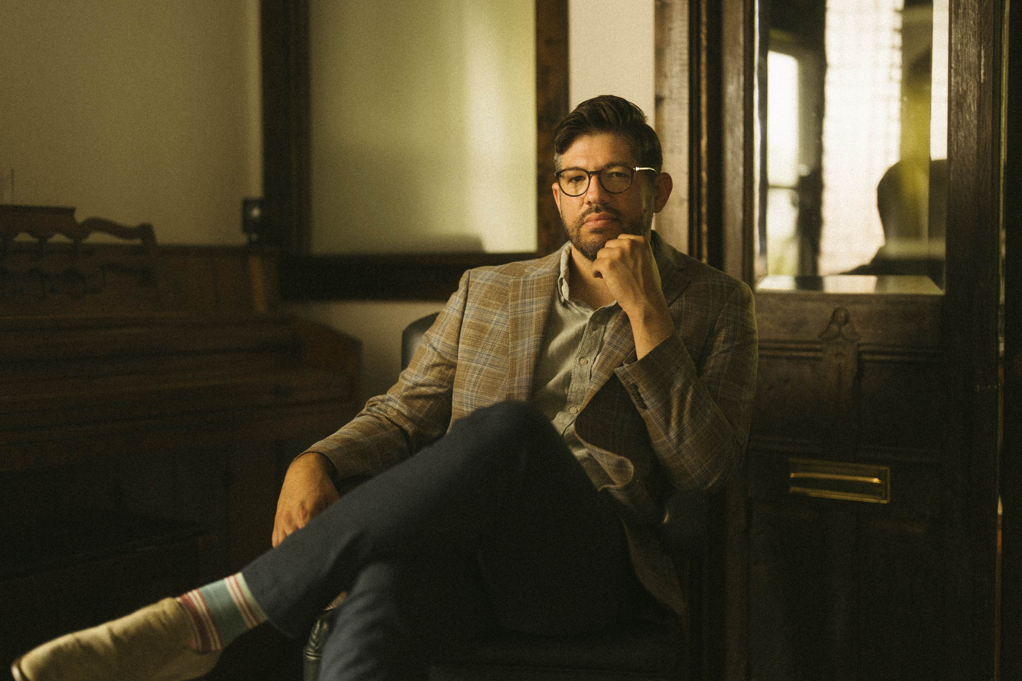 David A. Molina seated beside a piano